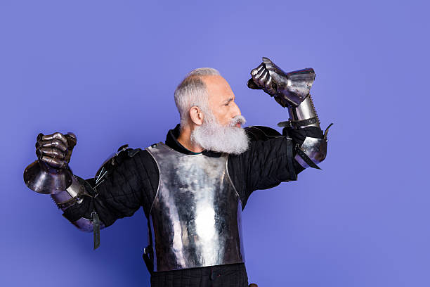 istock Bearded man in medieval knight armor playfully posing against a purple backdrop 2209316980