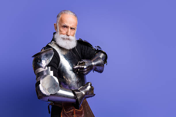 istock Senior man in medieval armor posing confidently against a vibrant purple background 2209316981