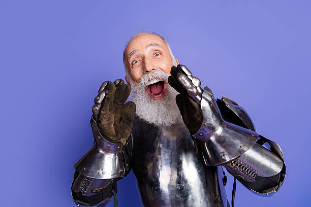 istock Excited mature man in medieval armor shouting with energetic expression against purple background 2209317006