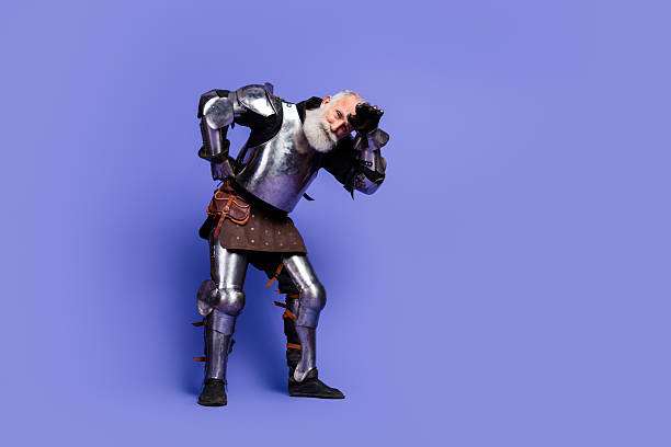 istock Medieval knight in full armor posing on a vivid purple background 2209317023