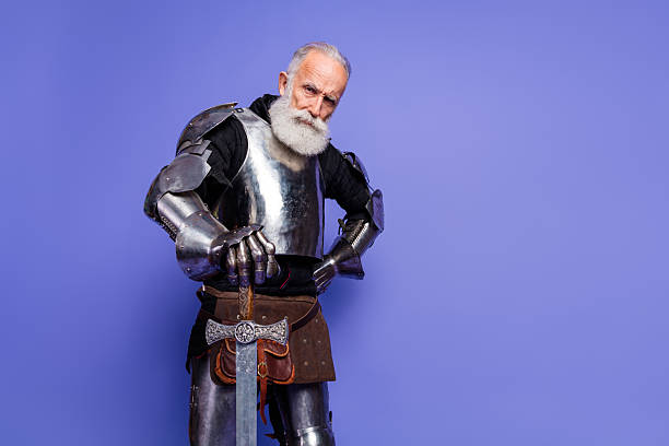 istock A mature bearded man wearing medieval armor standing confidently against a purple backdrop 2209317104
