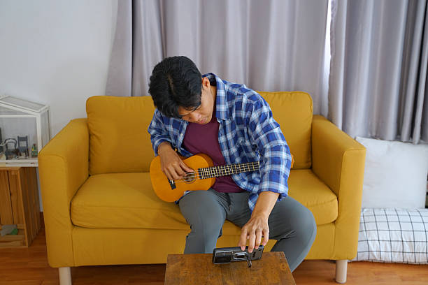 istock Young man is playing ukulele in living room. 2209323124