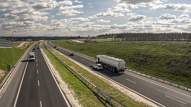 A Modern Highway with Moving Traffic Surrounded by Green Fields and Roadside Infrastructure