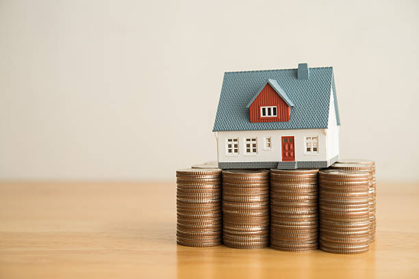 istock House on heap stack coins on wooden table white wall background copy space. 2209327131