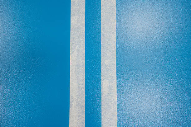 Two strips of masking tape on a blue epoxy resin floor coating during a painting job