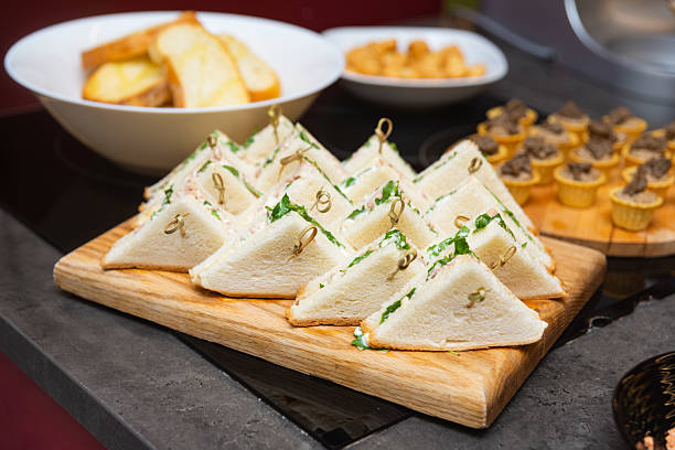 Triangle finger sandwiches on wooden board.