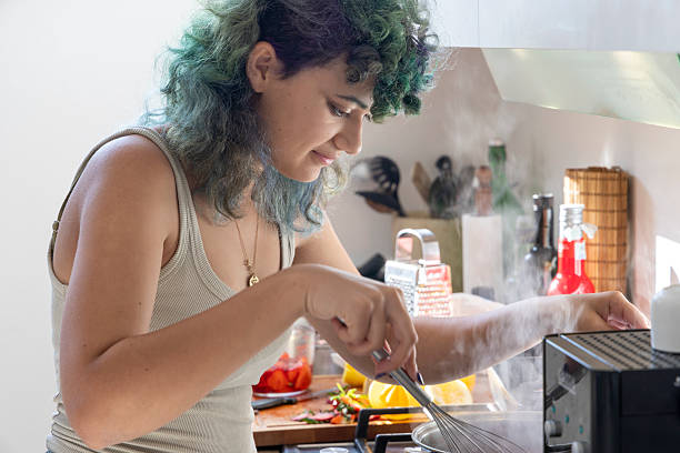 istock Generation Z woman stirs steaming pot in kitchen 2209327538