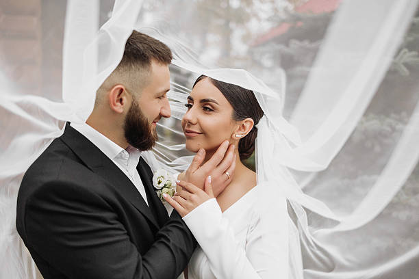 istock A bride and groom are standing under a white veil 2209330655