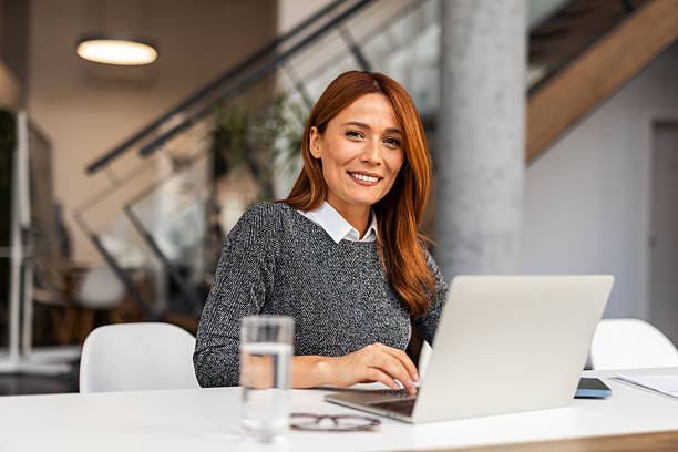 istock Professional Woman Smiling While Working on a Laptop in Modern Office 2209334312