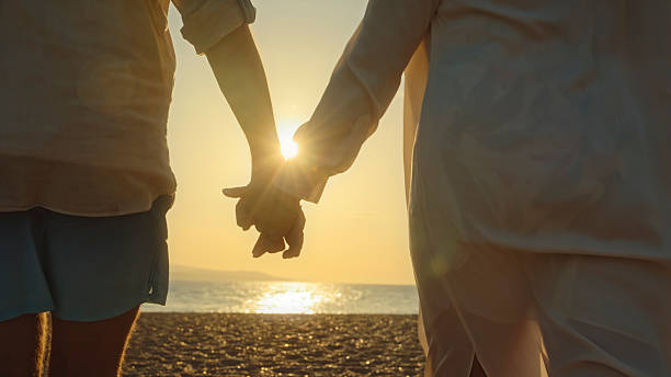 istock Mature Couple Holding Hands On Sandy Beach During Golden Hour Sunset 2209335457