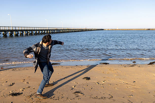 Man Skimming Stones Across Sea