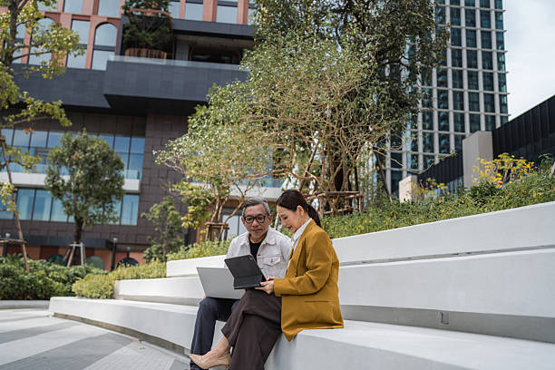 istock Two senior business professionals, collaborating outdoors, working together on their laptop 2209336198