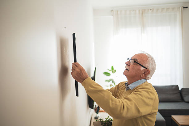 istock Senior man hanging a picture frame on a wall at home 2209337176