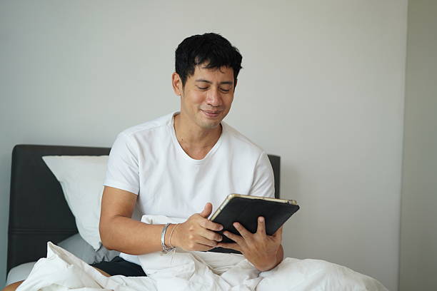 istock Happy man using tablet in bed in morning 2209337417