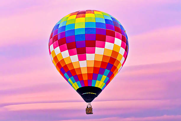 Colorful hot air balloon flying under orange sunset sky