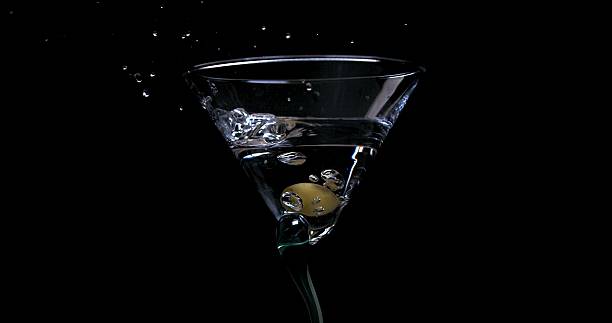 istock Olive falling into a glass with martini on a black background 2209346096