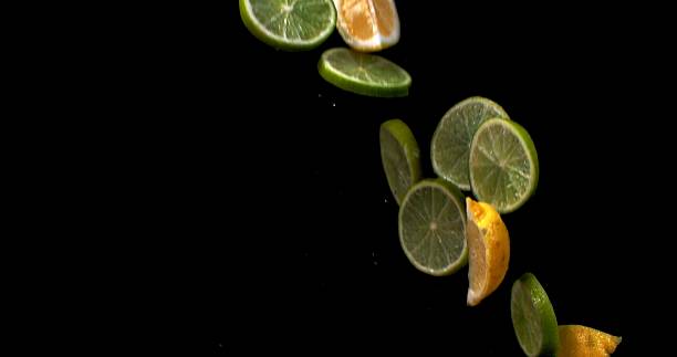 istock Lemon and lime sliced into wedges fly up and fall on a black background 2209346185
