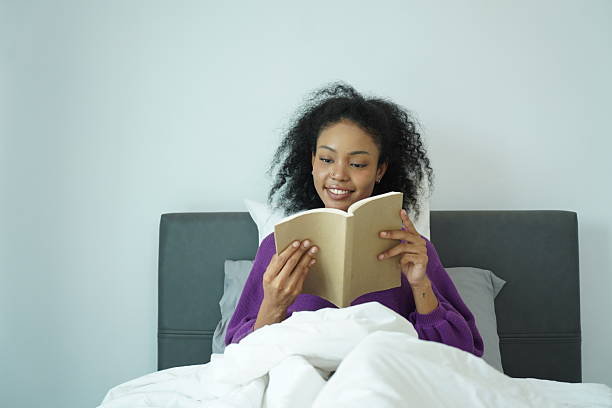 istock relaxed woman smiling while reading book during peaceful weekend morning in bed 2209346281