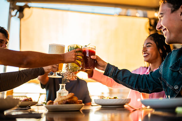 Young friends talking and toasting drinks at restaurant