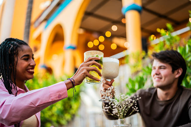 Young couple talking and toasting drinks at restaurant