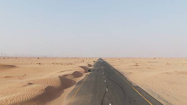 istock Vertical panning from a quadcopter. White car is driving on road in the desert 2209350785