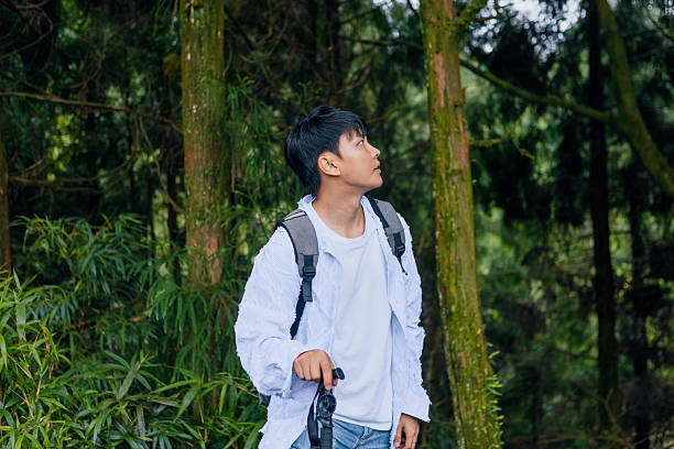 istock A young Asian man carrying a backpack and a hiking stick is exploring the forest, enjoying nature and a healthy lifestyle 2209352741