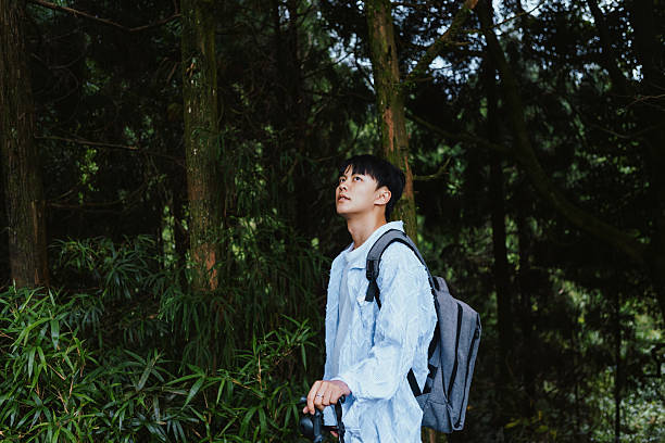 istock A young Asian man carrying a backpack and a hiking stick is exploring the forest, enjoying nature and a healthy lifestyle 2209354459