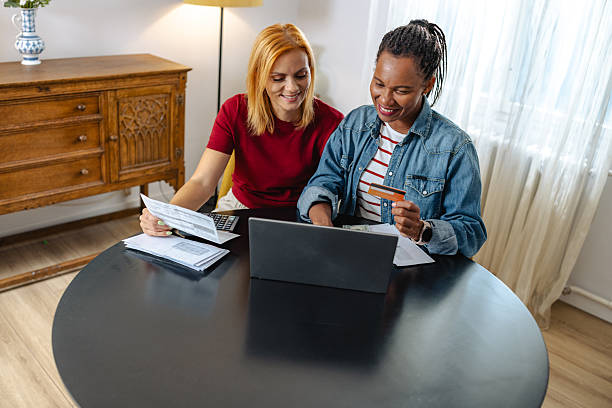 istock Diverse LGBT couple reviewing documents together at a table with a laptop 2209359677