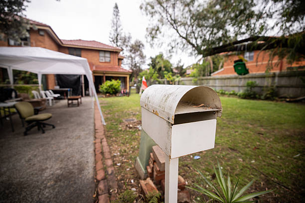 Classic white mailbox stands in the foreground, with a large, lush backyard and a charming house visible in the background.