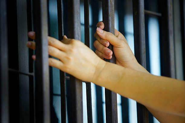 istock Hands Gripping Jail Bars in a Somber Shadows of Confinement 2209364554