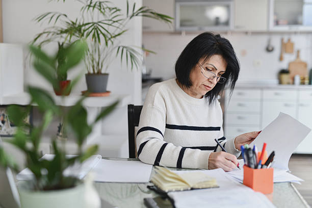 istock Concentrated Woman Examining Documents for Her Business on Dining Table at Home 2209366313