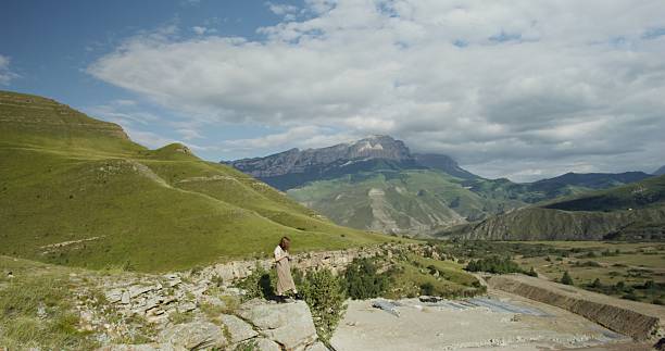 istock Russia, Caucasus. Young woman stands on hillside and looks at construction work 2209367653