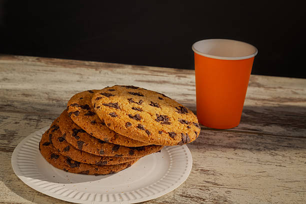 istock A cookie on the edge of a plate, ready to fall. Embodies the struggle between indulgence and dietary restrictions. A quick breakfast, rapid calories, and calorie content, along with food limitations. 2209368420