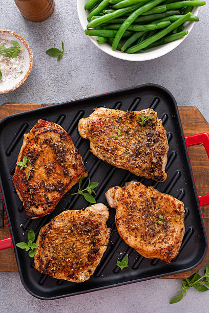 istock Pork chops with herbs and garlic grilled or sauteed on a pan 2209371303
