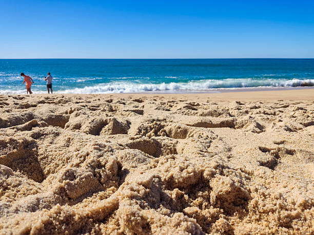 Serene beach scene featuring pristine sand, azure water, and a clear blue sky. Perfect for travel, vacation, or relaxation themed projects. Invites tranquility.