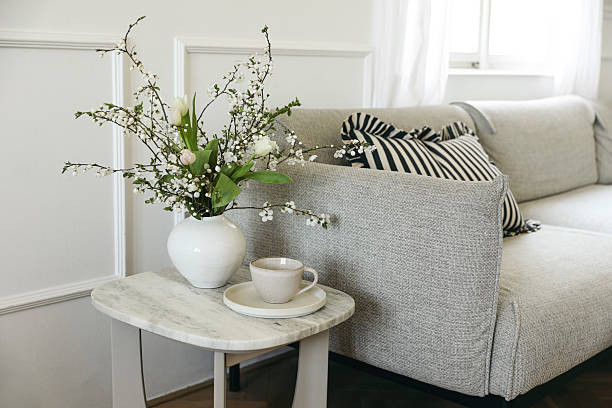 istock Springtime breakfast still life. Cup of coffee tea, marble table. Tulips blooming cherry plum tree branches bouquet in vase. Blurred cozy linen sofa with cushions. Elegant living room view. Home decor. 2209373030