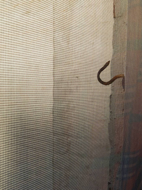 istock Picture Hanging Metal Hook on a wall behind Wire Mesh 2209373550