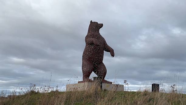 iant metal bear sculpture in Dunbar, Scotland by artist Andy Scott. Dramatic sky adds an imposing atmosphere to the artwork.