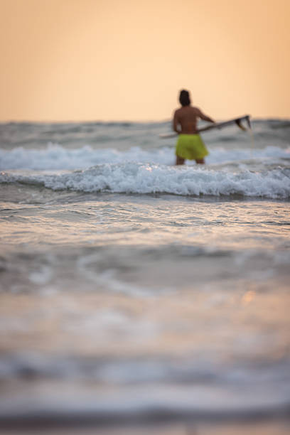 Young surfer woman is holding surf board on the beach.
