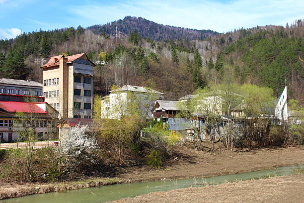 A group of houses on a hill. Outdoor. Grass. Sky. Tree. Mountain