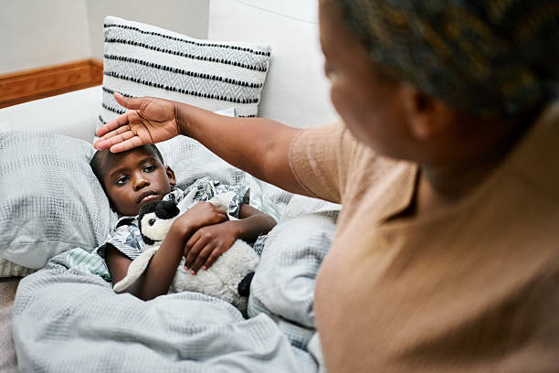 istock Caring African mother checking son's forehead for fever at Home 2209387997