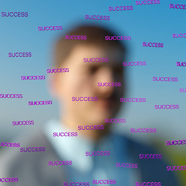 A digitally generated image depicting a blurred portrait of an individual with sharp, superimposed SUCCESS word across the foreground. The contrast between the defocused figure and the focused text emphasizes the dominance of the written words over the subject, suggesting themes of influence, obsession, or identity loss.