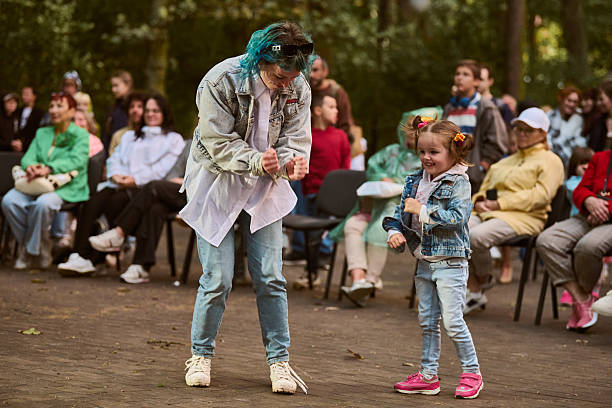 Kaliningrad, Russia - 11.08.2024 - Child and young female dance joyfully in park. Autumn colors, crowd in background, casual attire, vibrant atmosphere