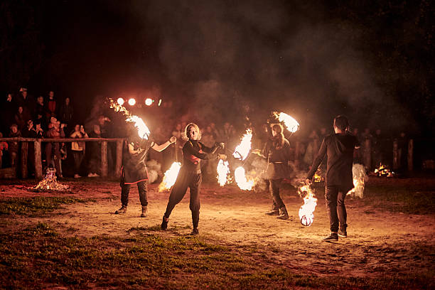 Kaliningrad, Russia - 10.09.2022 - Dancing fire show artists with fire poi at spectacular nighttime performance in dramatic light, fiery movements under night sky, spectators watching show