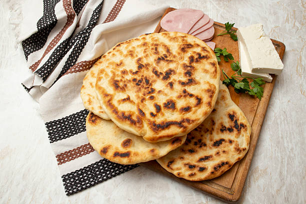 istock Fried pita bread stack on a wooden chopping board with ham slices and goat cheese, home made meal concept 2209393193