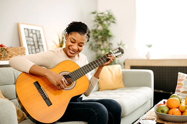 istock Woman sitting on sofa and playing guitar 2209393216