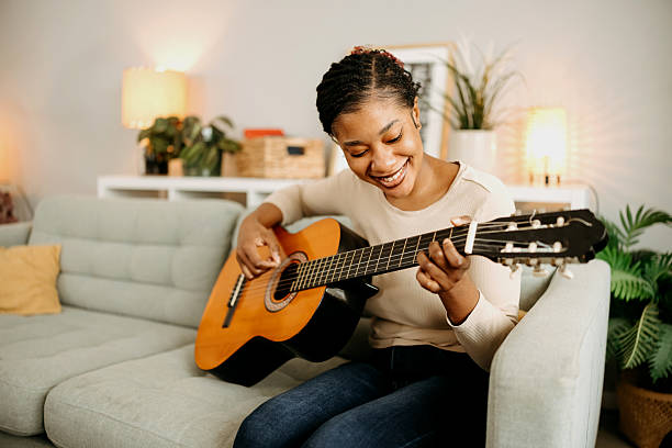 istock Woman sitting on sofa and playing guitar 2209393225
