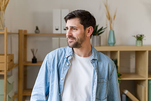 Pensive young man looking away while standing in his home office