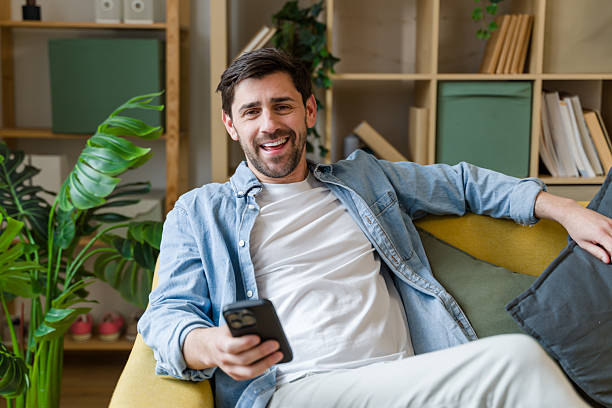 istock Young man relaxing on sofa using smartphone at home 2209395353