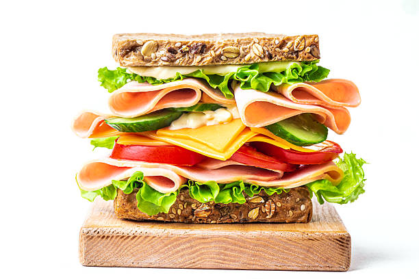 istock Layered sandwich with ham, cheese and vegetables on white 2209395858